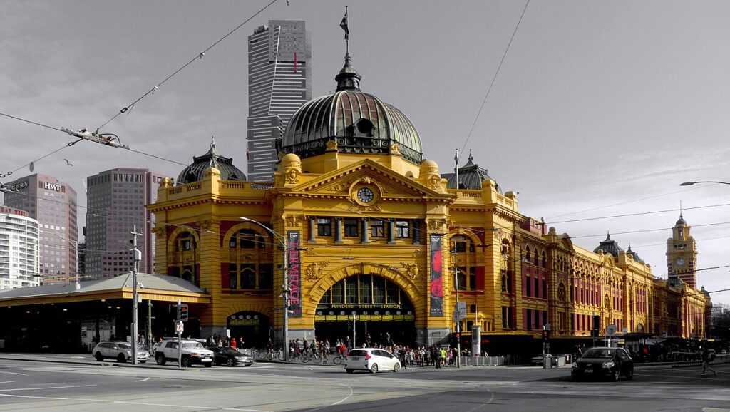 A bustling cityscape with a prominent clock tower, surrounded by a crowd of people. Melbourne cab service in the foreground.