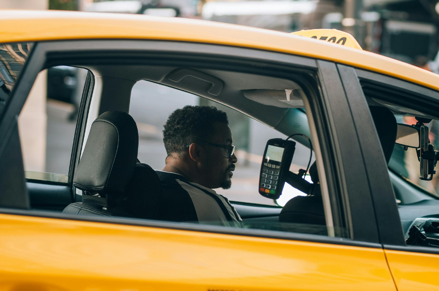 A man sitting in the driver's seat of a taxi in Melbourne cab service.